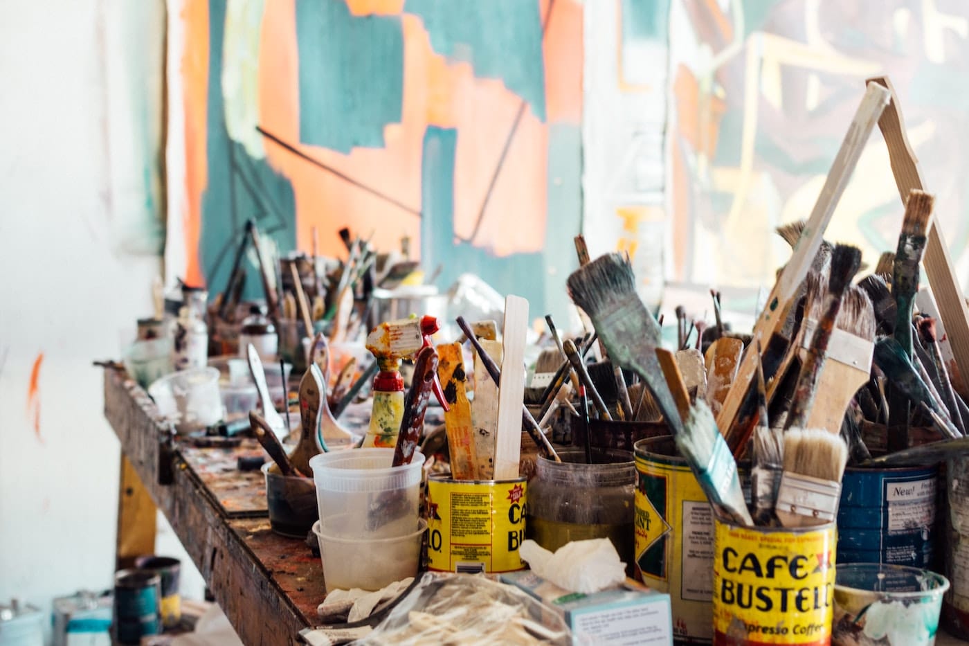 various paint brushes in cans with artwork in the background